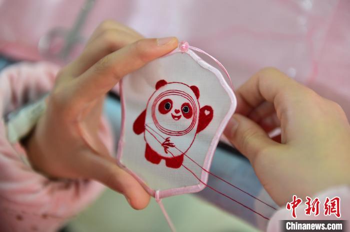 圖為一名小學生正在繡制2022年北京冬奧會吉祥物“冰墩墩”形象?！∮髟屏?攝