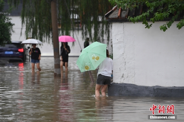 7月31日，市民行走在雨中的北京房山區(qū)瓦窯頭村。北京市氣象臺當(dāng)日10時發(fā)布分區(qū)域暴雨紅色預(yù)警信號。北京市水文總站發(fā)布洪水紅色預(yù)警，預(yù)計當(dāng)日12時至14時，房山區(qū)大石河流域?qū)⒊霈F(xiàn)紅色預(yù)警標(biāo)準(zhǔn)洪水。<a target='_blank' href='/'><p  align=