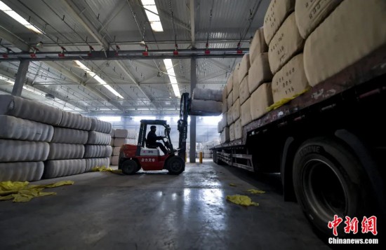新疆喀什綜合保稅區(qū)，喀什啟路國(guó)際貿(mào)易有限公司的倉(cāng)庫(kù)內(nèi)，工人正在裝載從塔吉克斯坦和烏茲別克斯坦進(jìn)口的棉花。劉新攝
