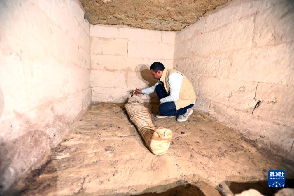 10月15日，在埃及明亞省考古現(xiàn)場(chǎng)，考古人員清理一座石鑿墓中的木乃伊。新華社發(fā)（艾哈邁德·戈馬攝）