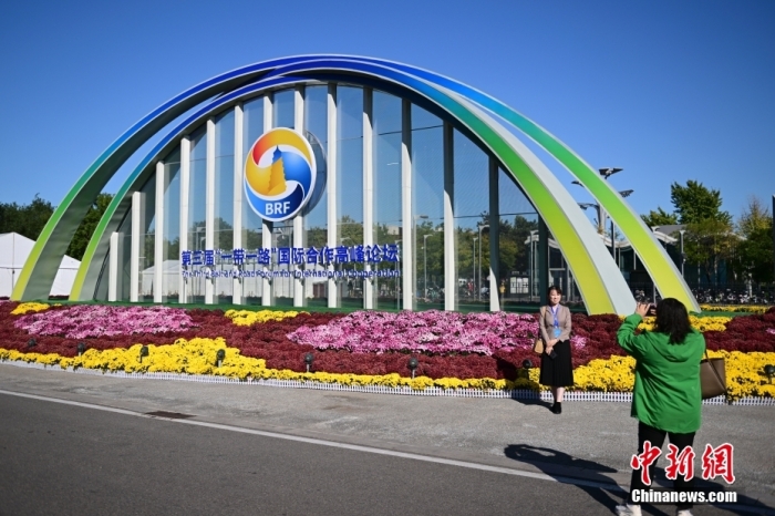 10月15日，北京，工作人員在國家會(huì)議中心外的第三屆“一帶一路”國際合作高峰論壇景觀布置前拍照留念。當(dāng)日，位于國家會(huì)議中心的第三屆“一帶一路”國際合作高峰論壇新聞中心啟動(dòng)試運(yùn)行。據(jù)悉，第三屆“一帶一路”國際合作高峰論壇將于10月17日至18日在北京舉行。<a target='_blank' href='/'><p  align=