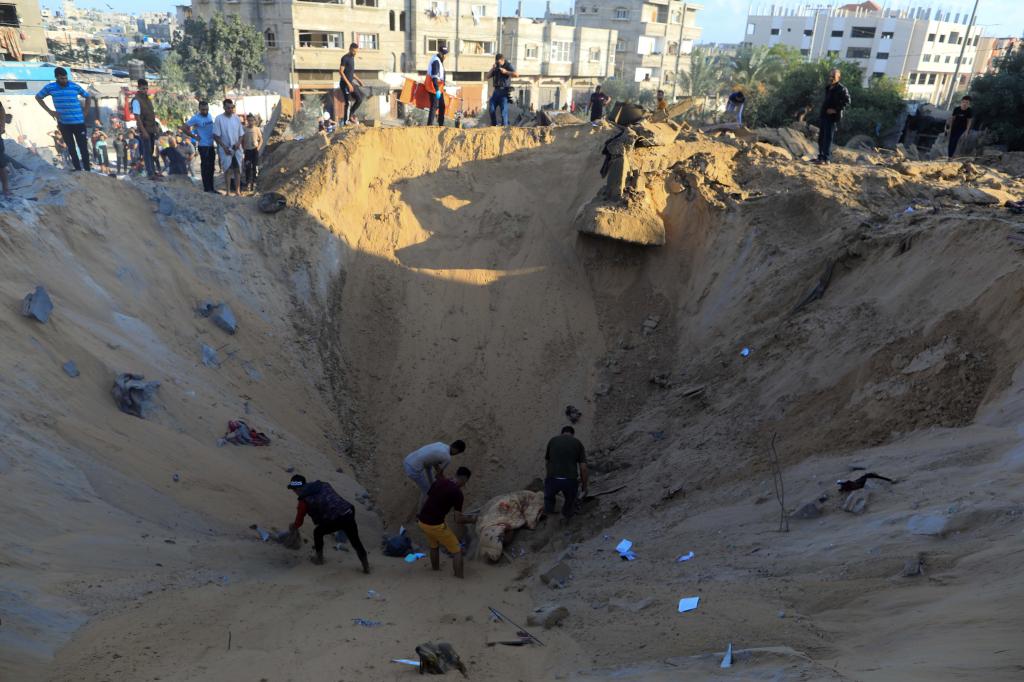 10月16日，在加沙地帶南部城市汗尤尼斯，人們在遭以色列襲擊后的建筑廢墟中救援傷者。 新華社發(fā)（亞西爾·庫迪 攝）
