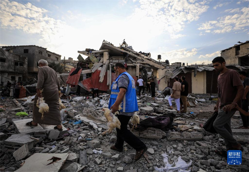 10月27日，在加沙地帶南部城市汗尤尼斯，人們經(jīng)過以軍襲擊后的房屋廢墟。
