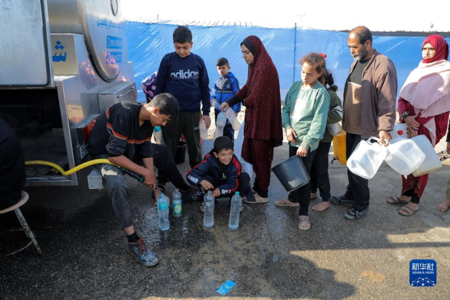 12月8日，在加沙地帶南部城市拉法一處臨時營地內(nèi)，人們排隊打水。新華社發(fā)（里澤克·阿卜杜勒賈瓦德 攝）