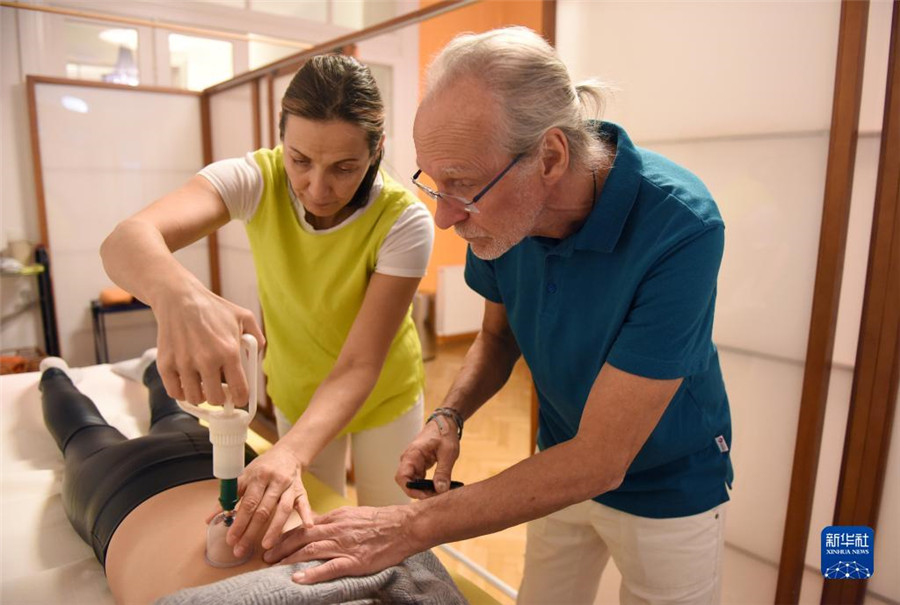 12月12日，在奧地利維也納，科格勒醫(yī)生（右）和助手在為病人進行拔罐治療。新華社記者 賀燦鈴 攝