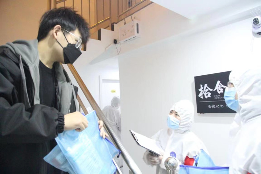 社區(qū)工作人員和志愿者身穿防護(hù)服上門(mén)送馬應(yīng)龍大健康防疫包。徐帥攝