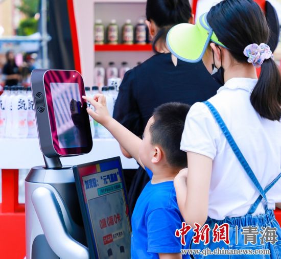 圖為一名小朋友正在和機(jī)器人“志愿者”進(jìn)行互動。 沐聞 攝