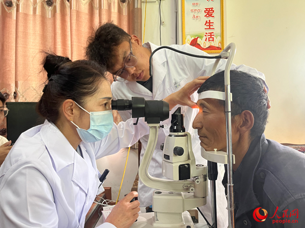 王紅英（左）和團隊成員為達熱村村民檢查眼睛。人民網(wǎng)記者 杜燕飛攝