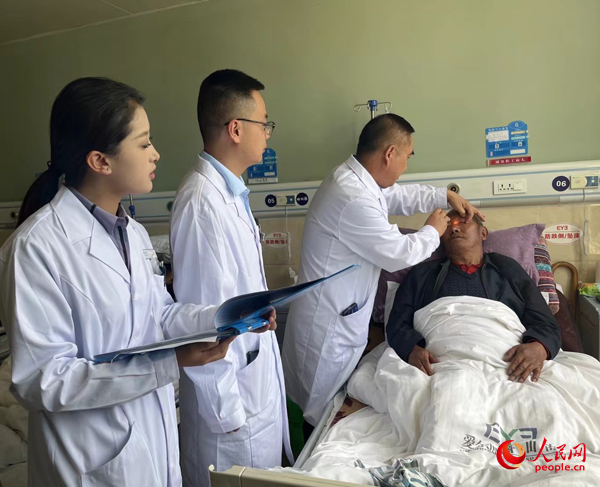 董光明（左三）帶領(lǐng)醫(yī)生對患者進行術(shù)前檢查。人民網(wǎng)記者 杜燕飛攝