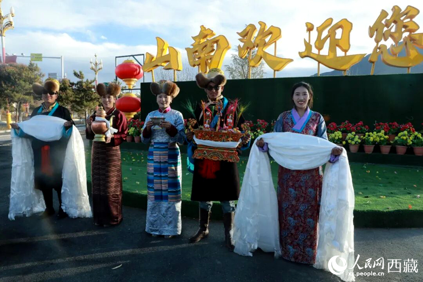 扎西曲登社區(qū)的居民在“山南歡迎您”標(biāo)志前，手持潔白哈達(dá)和切瑪，列隊(duì)迎接來(lái)自區(qū)內(nèi)外的游客，用最隆重的禮儀開(kāi)啟一場(chǎng)沉浸式藏歷新年民俗體驗(yàn)之旅。人民網(wǎng)記者 吳雨仁攝