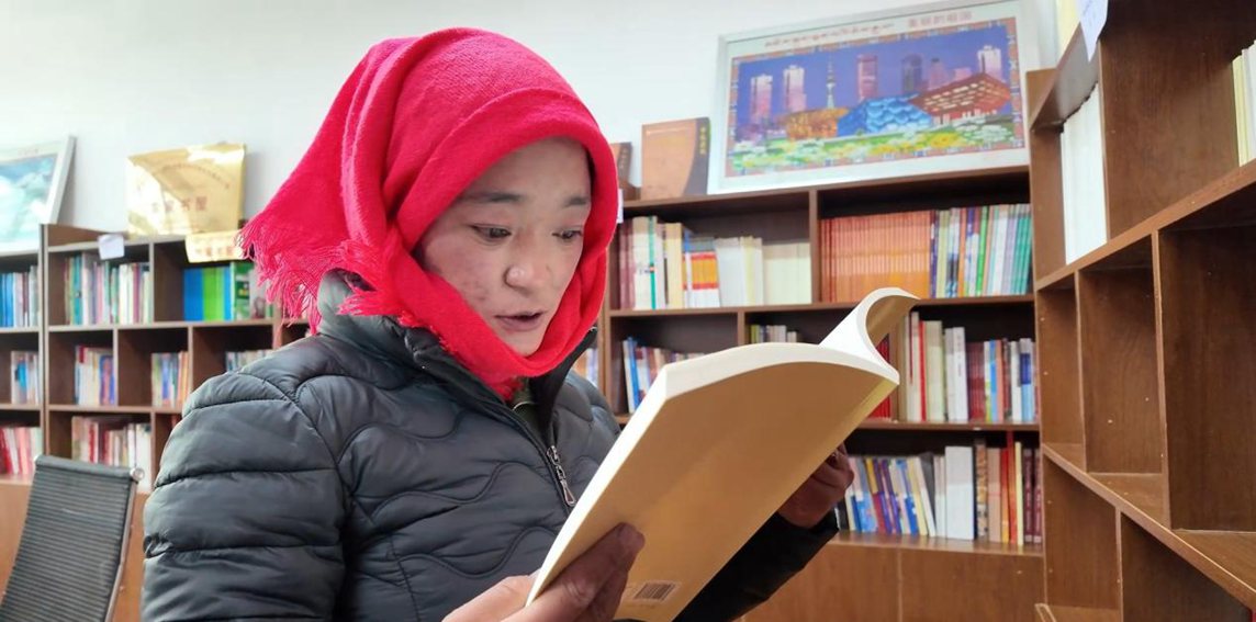 一名婦女正在認(rèn)真閱讀書籍。申扎縣融媒體中心供圖