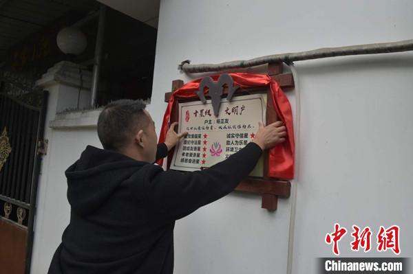 桂溪鎮(zhèn)渭溝村政府工作人員為“十星級文明戶”掛上牌匾。　楊勇 攝