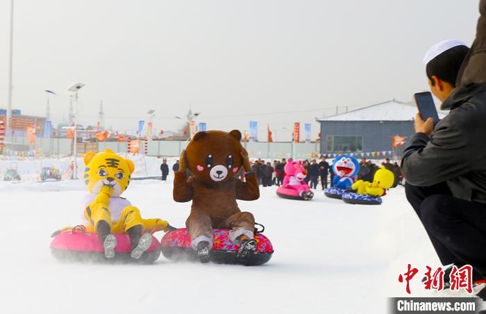 圖為臨夏市南龍鎮(zhèn)馬家莊村舉辦的鄉(xiāng)村文化旅游節(jié)上，游客穿著卡通服裝在體驗(yàn)雪上飛碟項(xiàng)目。近年來(lái)，臨夏州形成了“春賞花、夏避暑、秋摘果、冬玩雪”的全季節(jié)旅游產(chǎn)品體系。(資料圖) 高展 攝