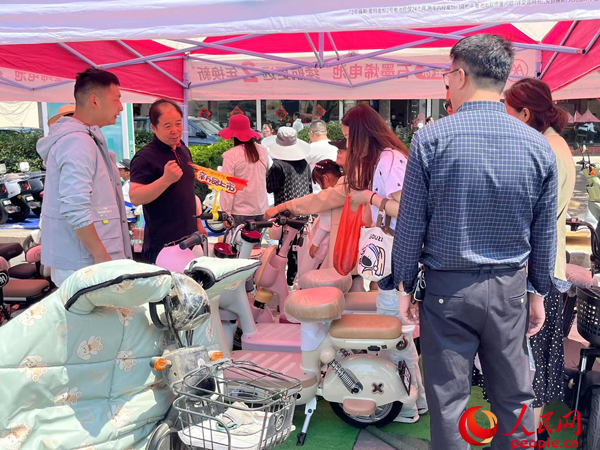 某電動(dòng)自行車品牌工作人員向消費(fèi)者介紹以舊換新相關(guān)情況。人民網(wǎng)記者 杜燕飛攝