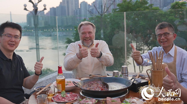 康寧顯示科技事業(yè)部全球拓建項(xiàng)目總監(jiān)軻寶華（中）和同事在重慶南濱路吃火鍋。人民網(wǎng)記者 蘇纓翔攝