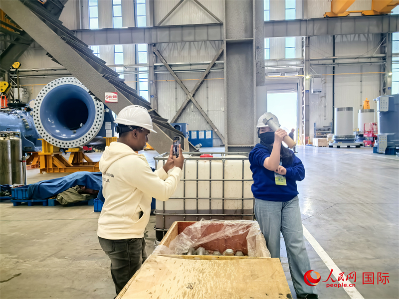 外媒記者掂量廠房內(nèi)的巨型螺栓。人民網(wǎng) 楊春燕攝