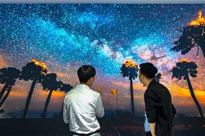 長春光博會希達(dá)電子展區(qū)，一位工作人員正在給一位觀眾講解。（長春新區(qū)供圖）