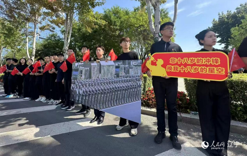 沈陽市人民廣場上，大學(xué)生們手持閱兵的圖片，告慰英烈。人民網(wǎng)記者 周頌雪攝