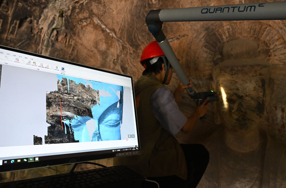 2025年4月9日，武漢大學文化遺產智能計算實驗室團隊成員在魏字洞使用關節(jié)臂掃描儀對佛像進行數字化掃描。圖片來源新華社