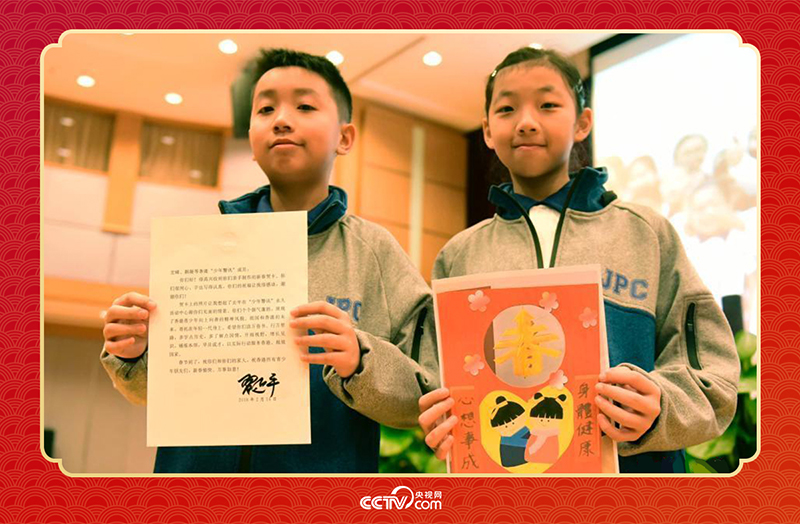 圖為香港“少年警訊”成員郭宏晞（左）展示習主席回信、羅顥凝（右）展示送給習主席的賀卡并合影。