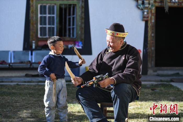 圖為米林縣扎西繞登鄉(xiāng)彩門村64歲的洛桑帶著孫子巴桑在院子的草地上玩耍?！『闻罾?攝