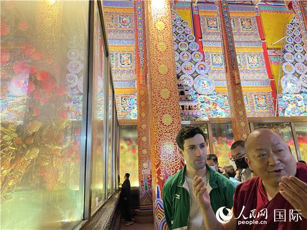 7月25日，省級(jí)非物質(zhì)文化遺產(chǎn)項(xiàng)目塔爾寺酥油花的代表性傳承人朋措堅(jiān)參（右）在塔爾寺酥油花館講解酥油花的制作過(guò)程。人民網(wǎng) 謝瑩攝