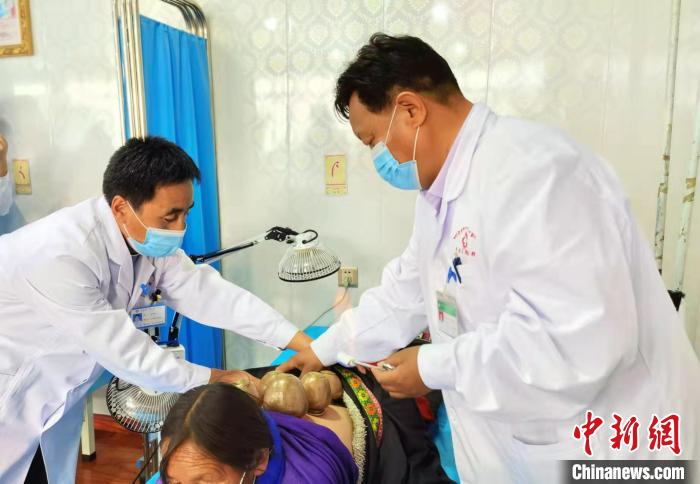 圖為看照加手把手帶徒弟加老(左一)進行拔罐療法。　張婧 攝