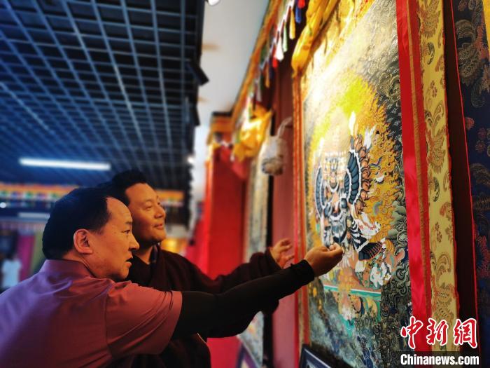 圖為久美尖措展示唐卡作品?！?zhí)砀?攝