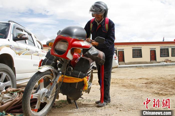圖為白瑪準(zhǔn)備騎摩托車(chē)巡湖。　趙朗 攝