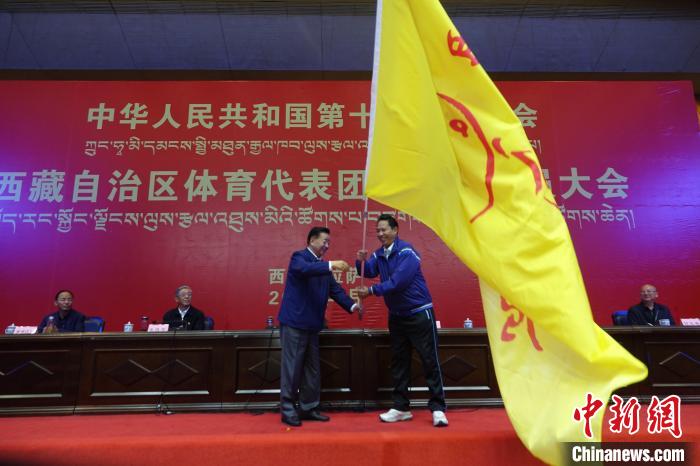 西藏自治區(qū)副主席甲熱·洛桑丹增授代表團(tuán)團(tuán)旗，西藏自治區(qū)體育局局長(zhǎng)尼瑪次仁接旗?！∪轿木?攝