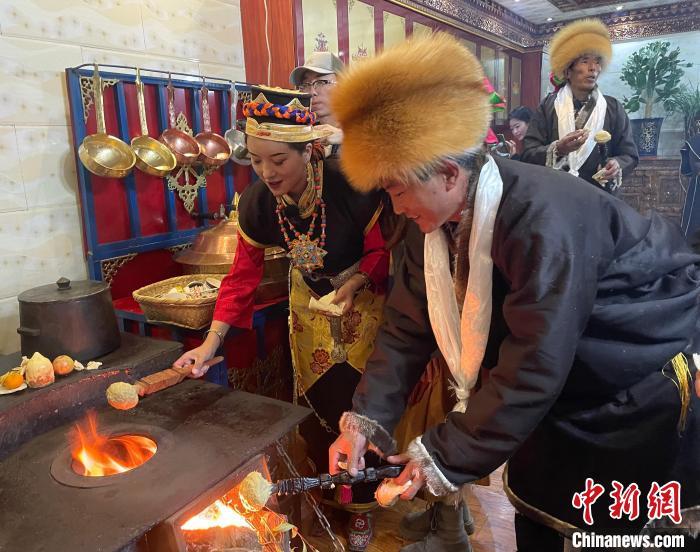 圖為人們在火上烤節(jié)日美食“結達”?！∪轿木?攝