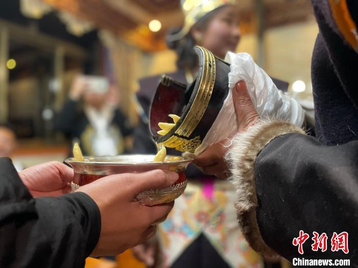 圖為主人在碗中斟滿青稞酒?！∪轿木?攝