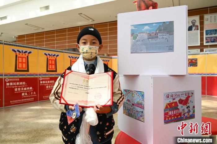 圖為一名獲獎學生與自己的繪畫作品合影?！≮w朗 攝