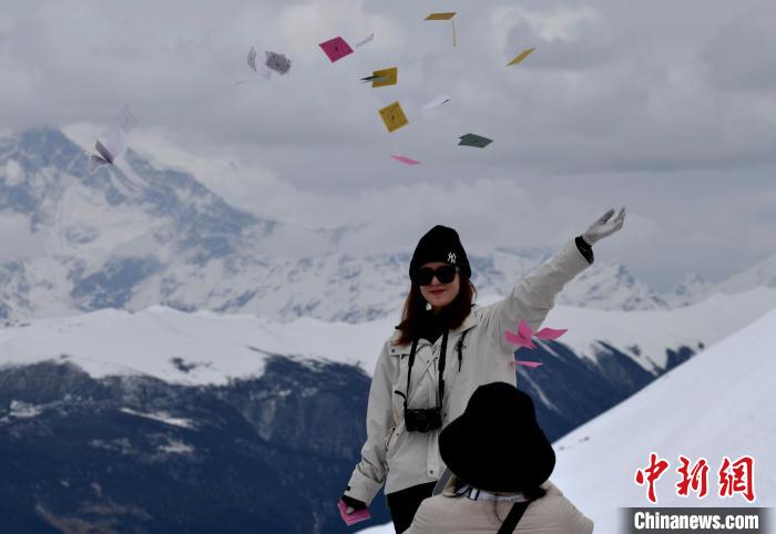 圖為5月14日，游客在西藏林芝色季拉山觀景臺拋灑“隆達”(風(fēng)馬旗，藏族民眾的一種祈福方式)?！±盍?攝