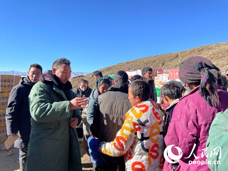 定日縣公安局干警頓珠次仁（左二）正在協(xié)助分發(fā)物資。人民網(wǎng)記者 郝潔攝