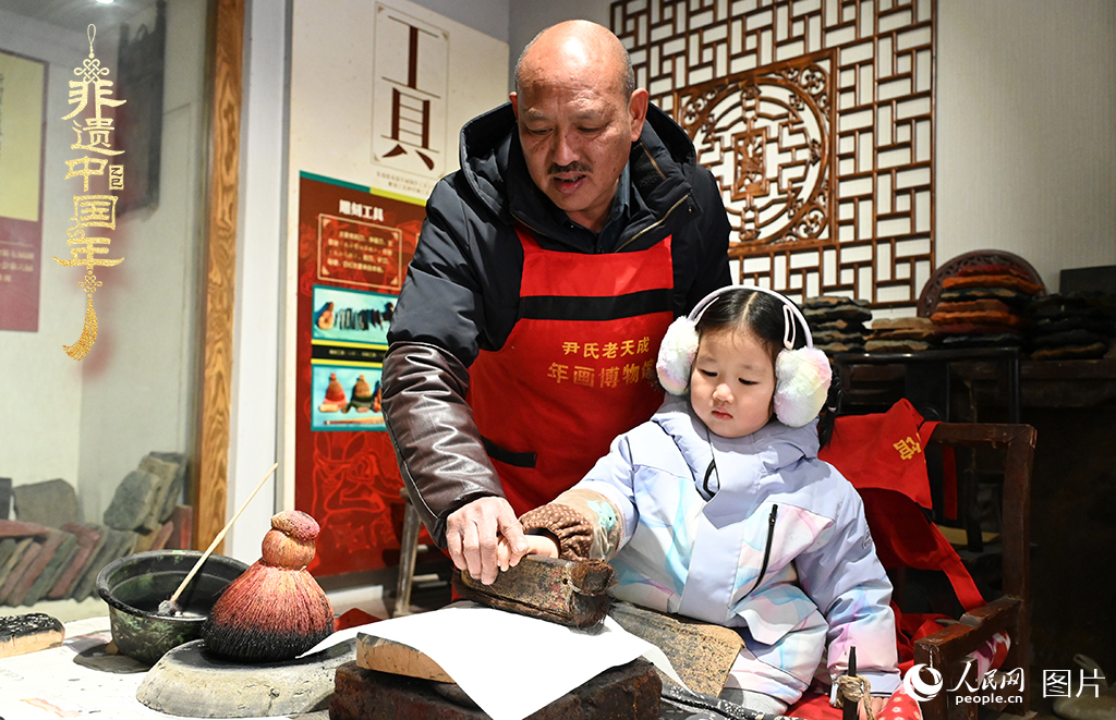 2025年1月27日，河南開封朱仙鎮(zhèn)木版年畫藝人尹國法指導(dǎo)小朋友研習(xí)年畫印制技藝。朱仙鎮(zhèn)木版年畫源自漢唐壁畫藝術(shù)，是中國木版年畫的鼻祖。2006年5月20日，朱仙鎮(zhèn)木版年畫經(jīng)國務(wù)院批準(zhǔn)列入第一批國家級非物質(zhì)文化遺產(chǎn)名錄。人民網(wǎng)記者 王玉興攝