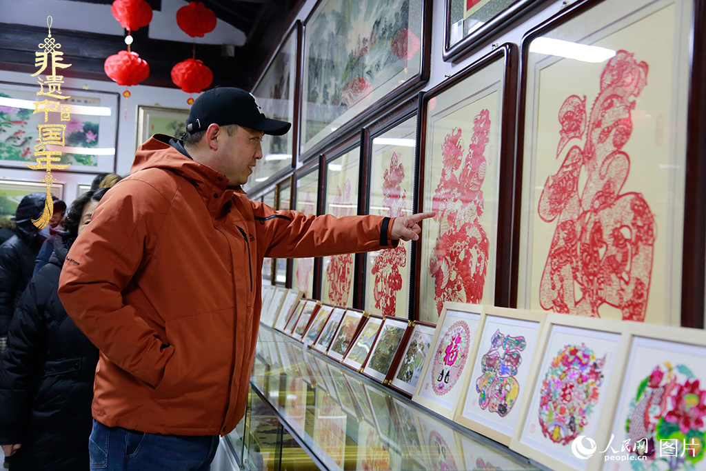 2025年1月23日，游客在天津楊柳青古鎮(zhèn)欣賞傳統(tǒng)剪紙作品，感受指尖上的古老藝術(shù)。人民網(wǎng)記者 崔新耀攝