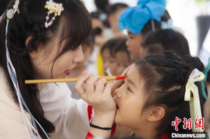 圖為老師在孩子們額頭上點(diǎn)上雄黃，驅(qū)邪辟禍?！《^生 攝