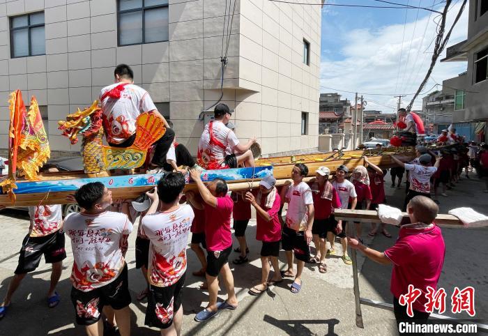圖為5月29日，長(zhǎng)樂江田鎮(zhèn)村民們肩扛著新龍舟舉行入水前游街儀式?！埍?攝