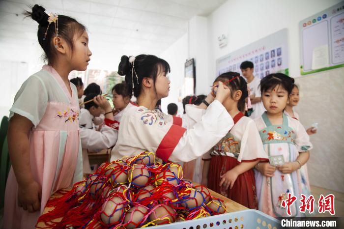 圖為幼兒園的老師們穿上漢服為小朋友們戴上彩蛋，寓意著幸福安康。　董觀生 攝